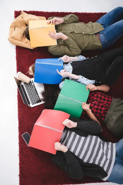 Молодые подростки лежат на ковре с ноутбуками и ноутбуками — стоковое фото