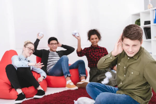 Junge Studenten sitzen auf Sesseln und werfen Papier in Mitschüler — Stockfoto