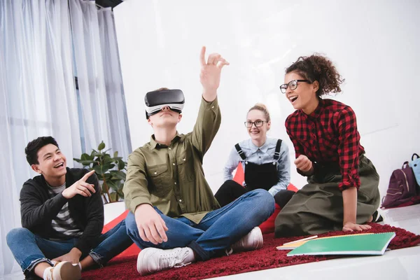 Мальчик в очках виртуальной реальности сидит на ковре с друзьями — стоковое фото