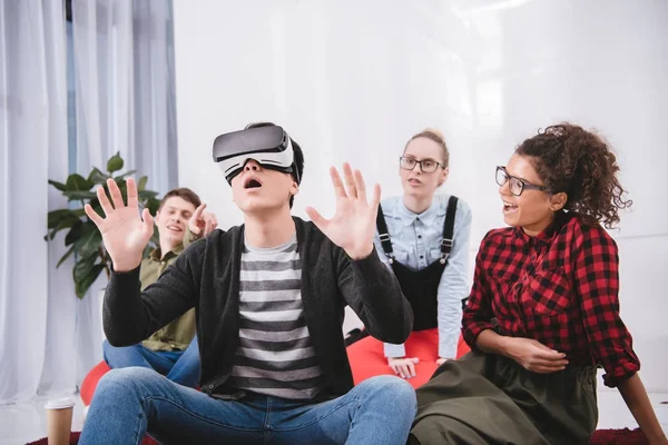 Menino em óculos de realidade virtual sentado no tapete com amigos — Fotografia de Stock