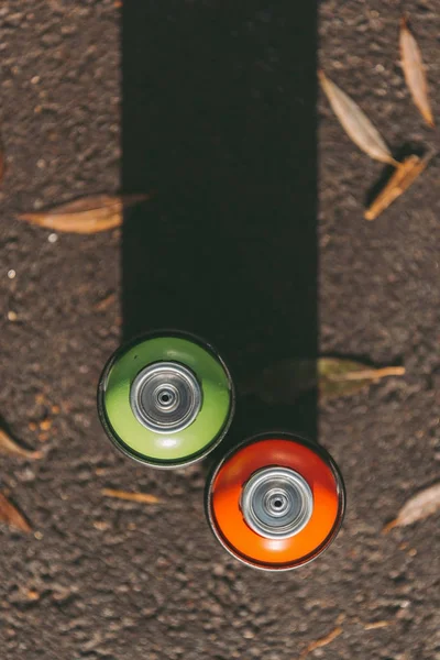 Vue du dessus des boîtes de conserve avec peinture rouge et verte en aérosol sur asphalte avec ombre — Photo de stock