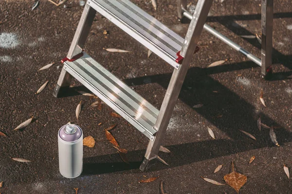 Close up of ladder and can with colorful spray paint on asphalt — Stock Photo