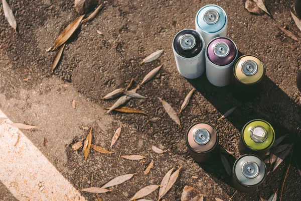 Vista superior de latas con pintura en aerosol de colores para graffiti sobre asfalto - foto de stock