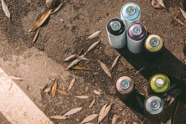 Top view of cans with colorful spray paint for graffiti on asphalt — Stock Photo