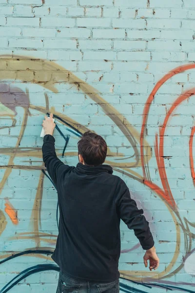 Vue arrière de l'homme peinture graffiti coloré sur le mur — Photo de stock