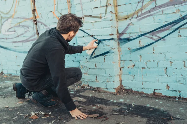 Artista callejero pintando graffiti colorido en la pared del edificio - foto de stock