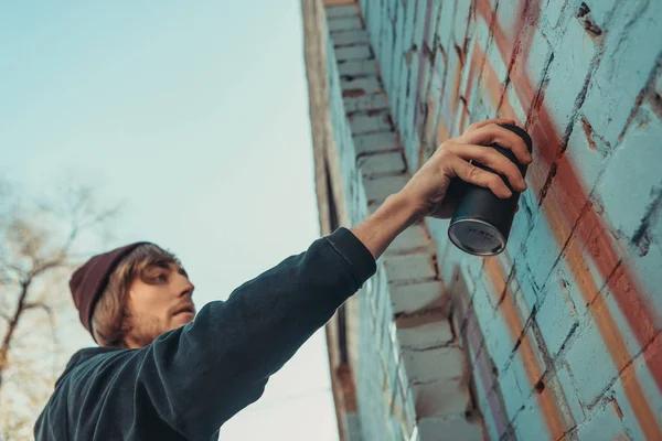Человек рисует красочные граффити на стене здания — стоковое фото