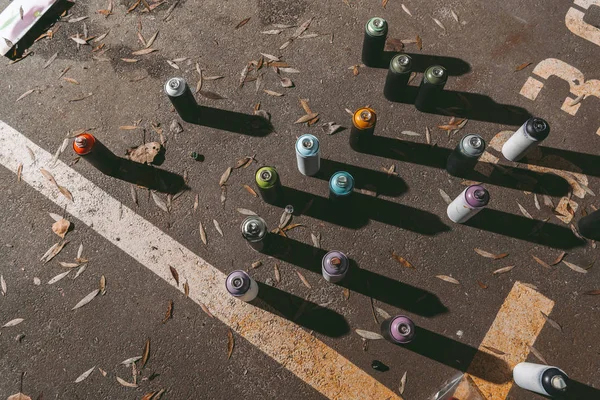 Top view of cans with colorful spray paint for graffiti on asphalt — Stock Photo