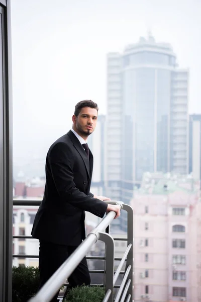 Portrait of young pensive man in suit standing at restaurant balcony — Stock Photo