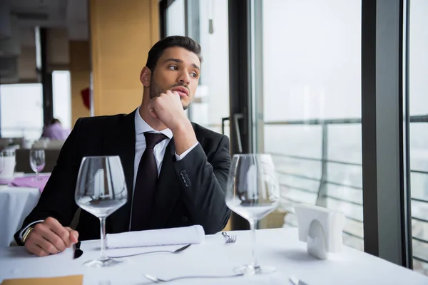 Pensive man in suit looking away while waiting for order in restaurant — Stock Photo