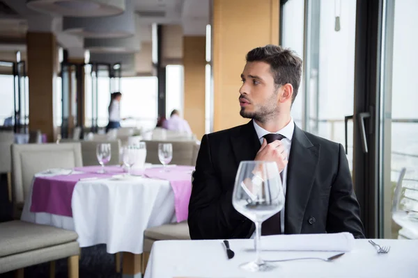 Hombre pensativo en traje mirando hacia otro lado mientras espera el pedido en el restaurante - foto de stock