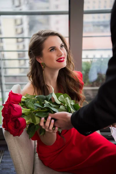 Partial view of man presenting bouquet of flowers for girlfriend during romantic date in restaurant, st valentine day — Stock Photo