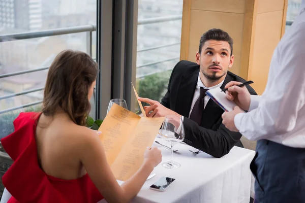 Selective focus of man making order on st valentine day romantic date with girlfriend in restaurant — Stock Photo