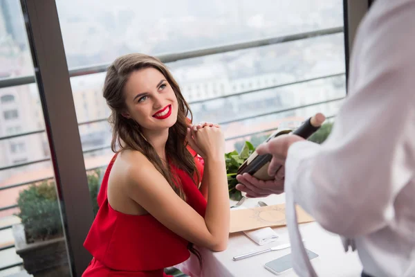Selective focus of cheerful woman looking at waiter with bottle of wine in hands — Stock Photo