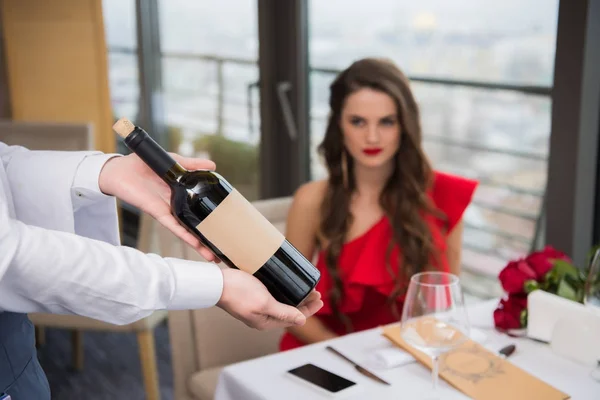 Foco seletivo do garçom segurando garrafa de vinho no restaurante — Fotografia de Stock