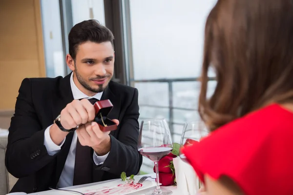 Partial view of young man presenting gift to girlfriend on romantic date in restaurant — Stock Photo