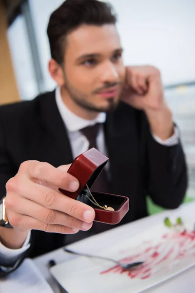 Selective focus of young man presenting gift to girlfriend on romantic date in restaurant — Stock Photo