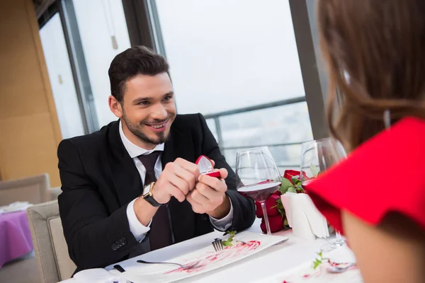 Частичный взгляд улыбающегося мужчины, делающего предложение девушке на романтическом свидании в ресторане на день Святого Валентина — стоковое фото