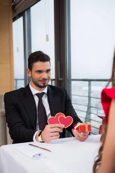 Junger Mann überreicht Freundin bei romantischem Date im Restaurant Geschenk — Stockfoto