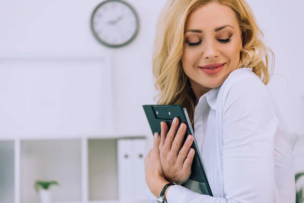 Hermosa mujer abrazando portapapeles con documentos - foto de stock