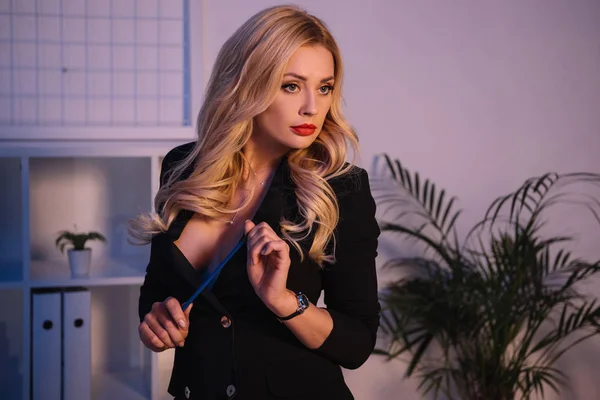 Seductive woman in jacket holding pencil and looking away — Stock Photo