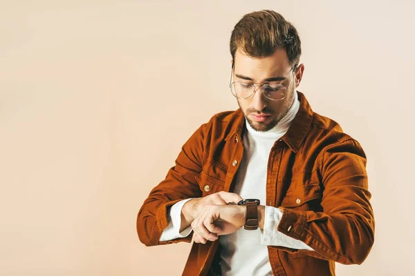 Retrato de homem bonito verificando o tempo no relógio isolado no bege — Fotografia de Stock