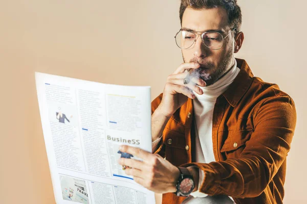 Portrait of businessman with cigar reading newspaper isolated on beige — Stock Photo