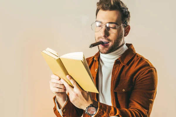 Portrait of young man with cigar reading book isolated on beige — Stock Photo