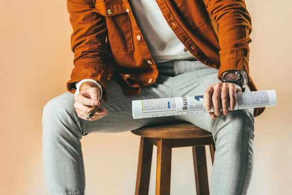 Cropped shot of businessman with cigar and business newspaper isolated on beige — Stock Photo