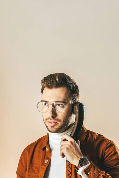 Ritratto di uomo elegante pensieroso che distoglie lo sguardo mentre parla al telefono isolato sul beige — Foto stock