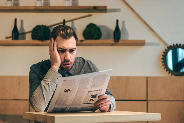 Retrato de empresário chocado lendo jornal à mesa no café — Fotografia de Stock