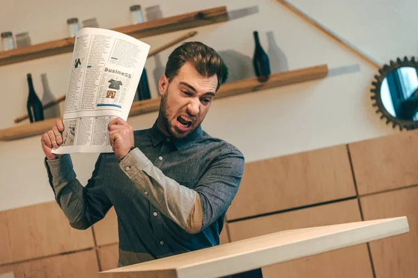 Portrait of angry businessman throwing newspaper at table in cafe — Stock Photo