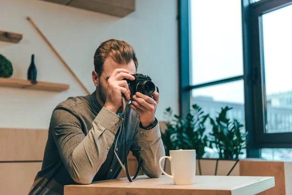 Verdunkelte Sicht auf Mann, der in Café mit Fotokamera fotografiert — Stockfoto