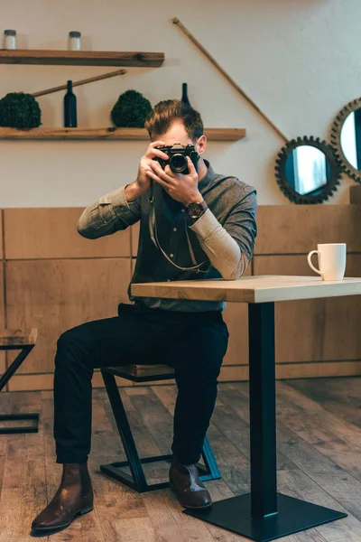 Obscured view of man taking picture on photo camera in cafe — Stock Photo