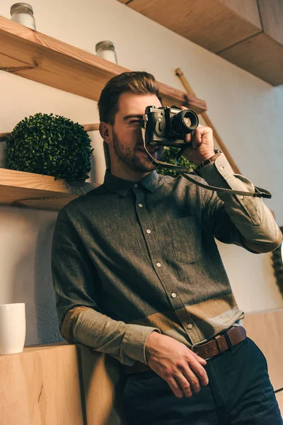 Portrait of stylish man taking picture on photo camera in cafe — Stock Photo