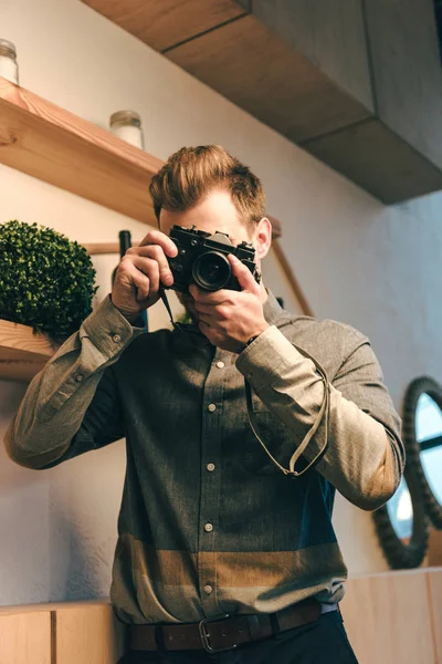 Verdunkelter Blick auf stilvollen Mann, der Foto auf Fotokamera im Café macht — Stockfoto
