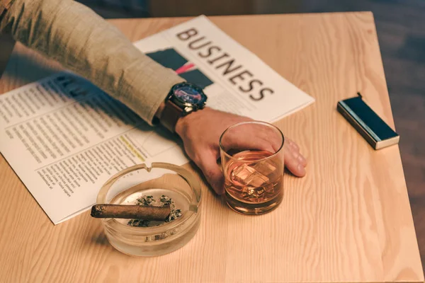 Schnappschuss eines Geschäftsmannes, der mit einem Glas Cognac, Zeitung und Zigarre im Aschenbecher im Café sitzt — Stockfoto