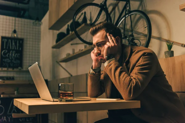 Стресова людина дивиться на екран ноутбука під час роботи в кафе — стокове фото