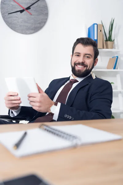 Retrato de hombre de negocios alegre con tableta en el lugar de trabajo en la oficina - foto de stock