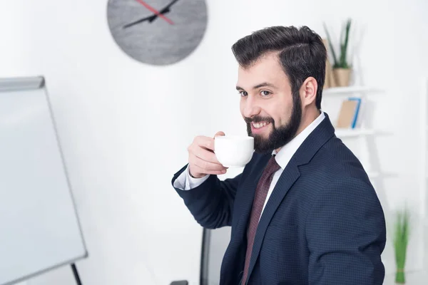 Retrato de homem de negócios sorrindo bebendo café no escritório — Fotografia de Stock