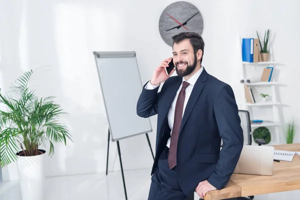 Retrato del hombre de negocios sonriente hablando en el teléfono inteligente en la oficina - foto de stock