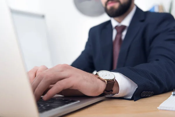 Vista parcial del hombre de negocios en traje escribiendo en el ordenador portátil - foto de stock