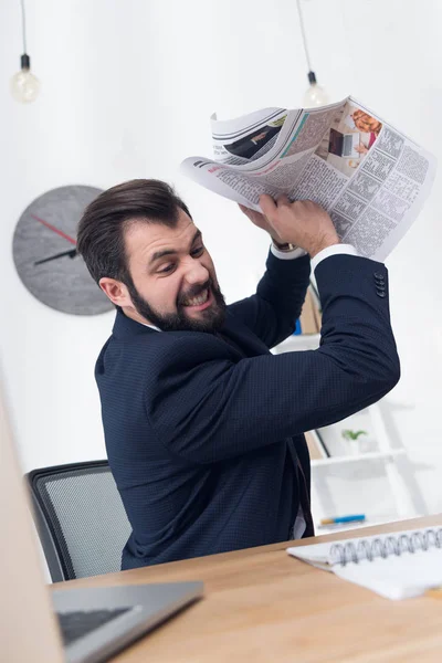Retrato del hombre de negocios enojado lanzando periódico al lugar de trabajo - foto de stock