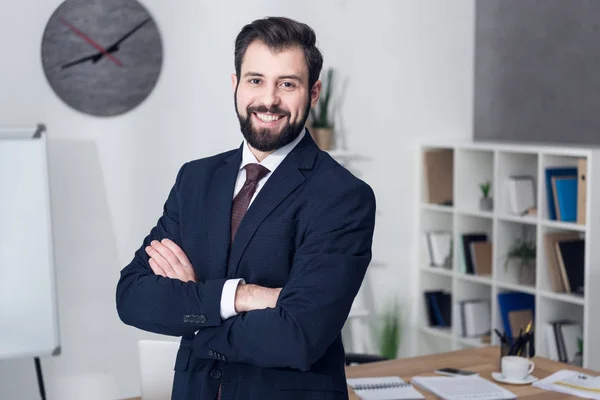 Porträt eines lächelnden Geschäftsmannes mit verschränkten Armen im Amt — Stockfoto