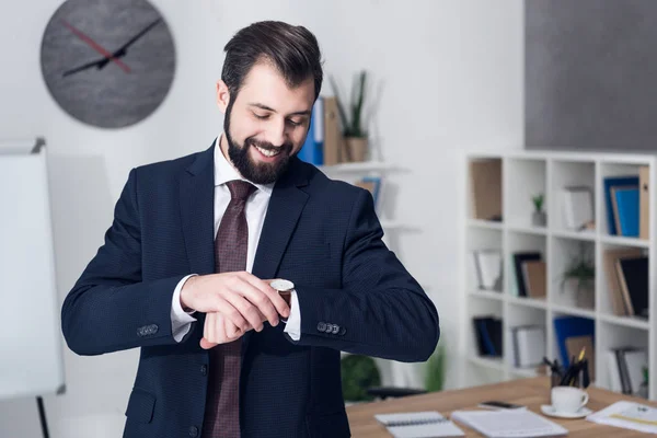 Porträt eines lächelnden Geschäftsmannes, der die Zeit im Amt kontrolliert — Stockfoto