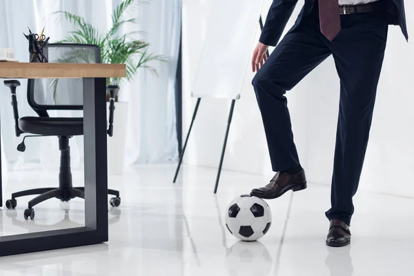 Обрізаний знімок бізнесмена з футбольним м'ячем на робочому місці в офісі — стокове фото