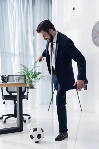 Jeune homme d'affaires en costume jouant au football au bureau — Photo de stock