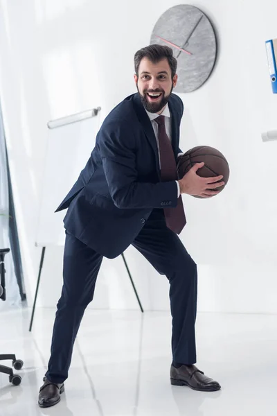 Молодой бизнесмен в костюме играет в баскетбол в офисе — стоковое фото