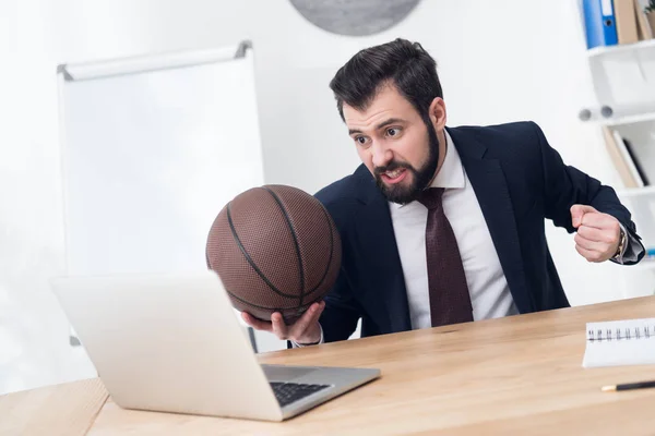 Angry businessman with basketball ball at workplace in office — Stock Photo