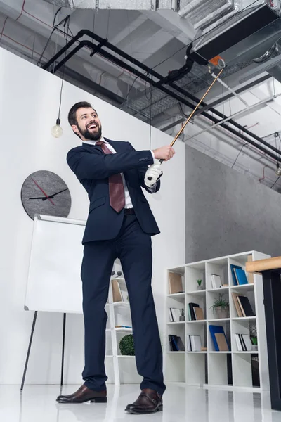 Visão de baixo ângulo de homem de negócios sorridente em terno jogar golfe no escritório — Fotografia de Stock